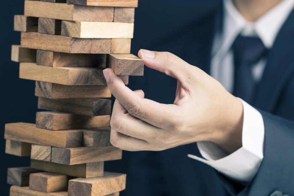 This Is the Dividend Stock I’d Hold Through Market Volatility man in business suit pulls a piece out of wobbly wooden tower